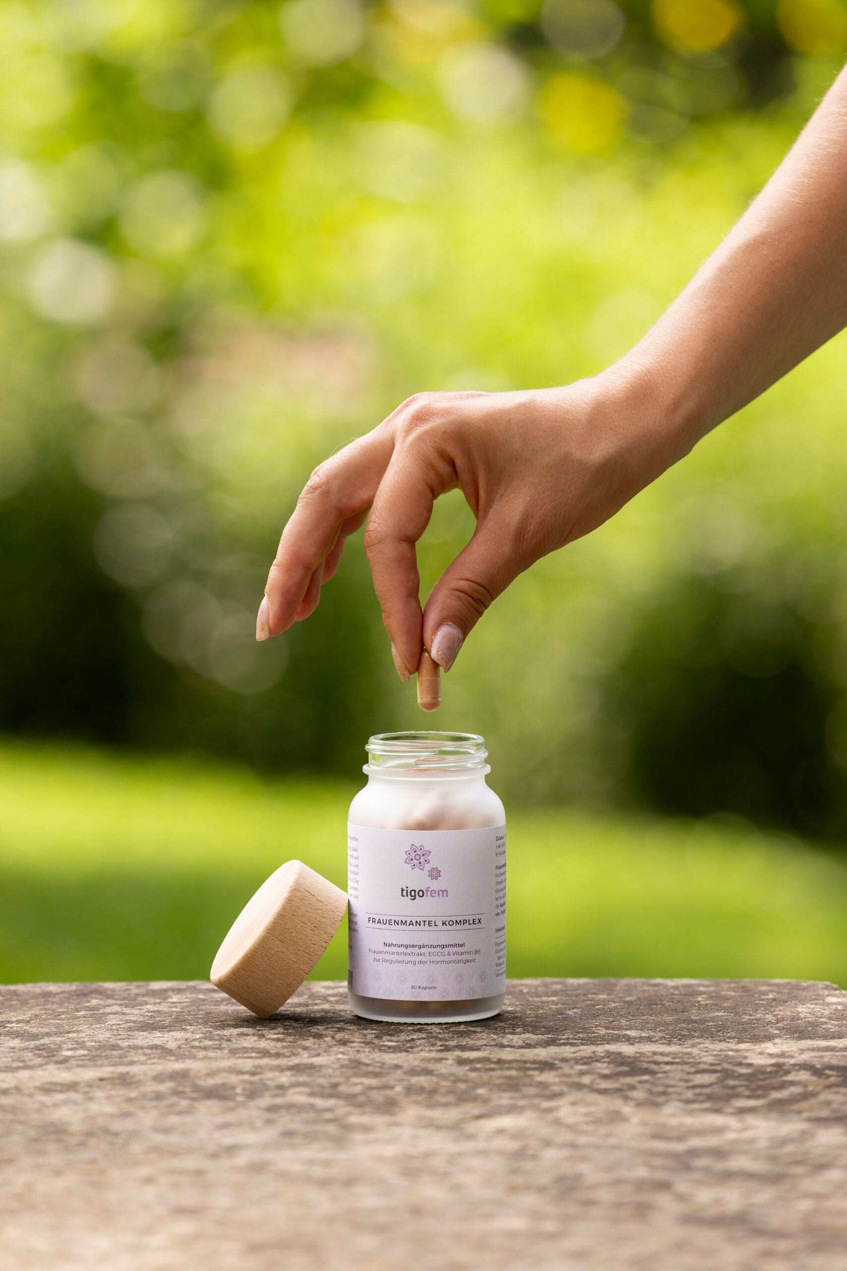 Frauenmantel Extrakt Kapsel wird aus tigofem Glasflasche für Hormon-Balance im Garten entnommen.