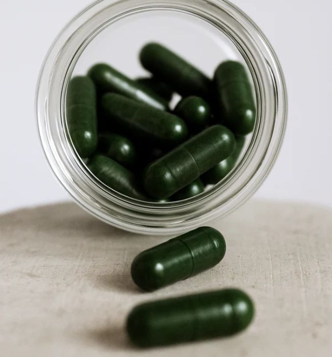 Detailaufnahme der grünen tigovit EGCG Kapseln in einer Glasflasche des nachhaltigen Grüntee-Extrakt Starter Pakets.